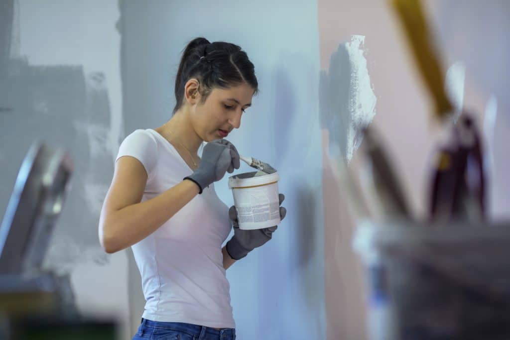 Young woman with hearing aid painting walls