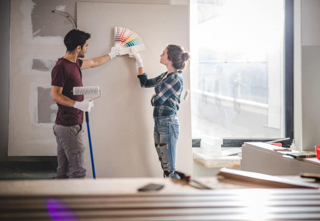 Young couple choosing the right color for their wall while renovating apartment.